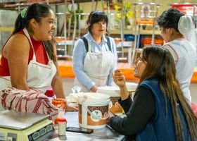 Women interacting joyfully in a Ciudad de México kitchen, promoting teamwork and culture.