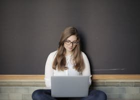 A young woman sitting indoors using a laptop, embodying the freelance and digital nomad lifestyle.
